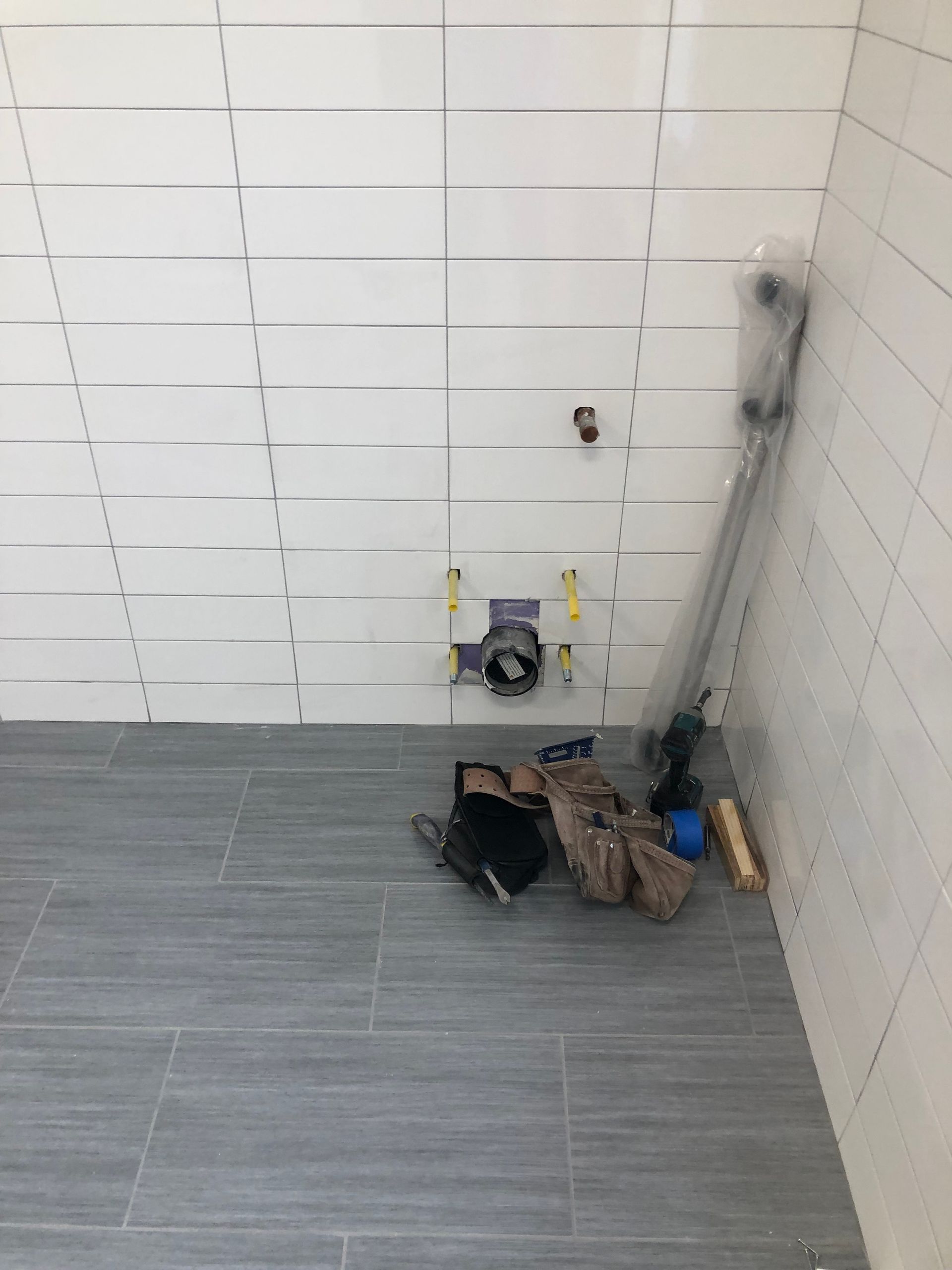 A bathroom with white tiles and a gray tile floor.