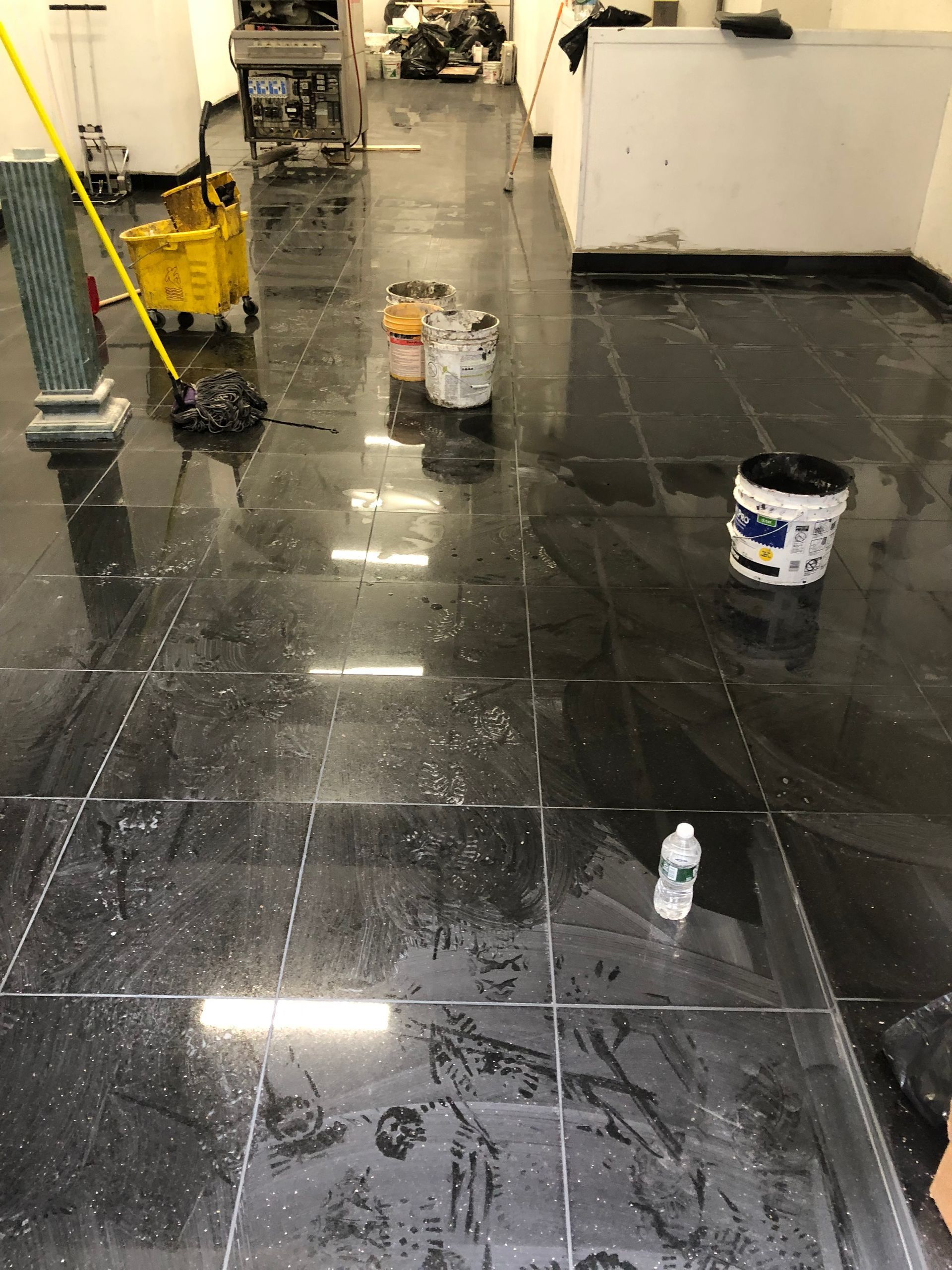 A dirty floor with buckets and a mop on it