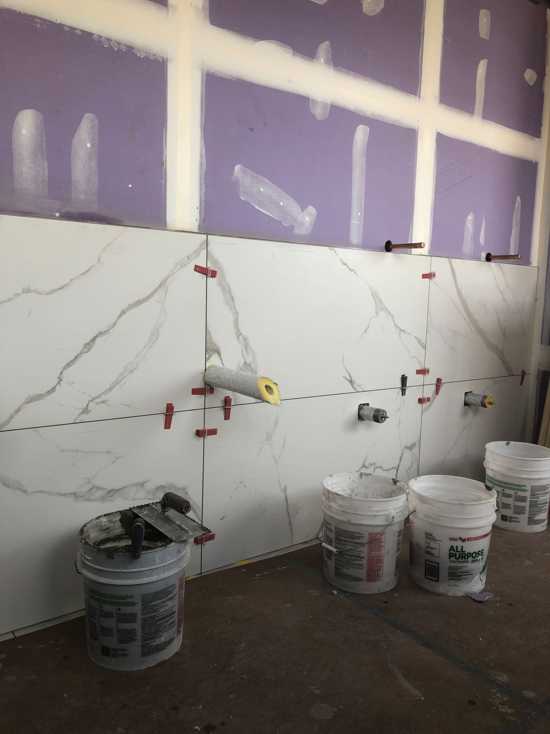 A bathroom under construction with buckets of paint on the floor