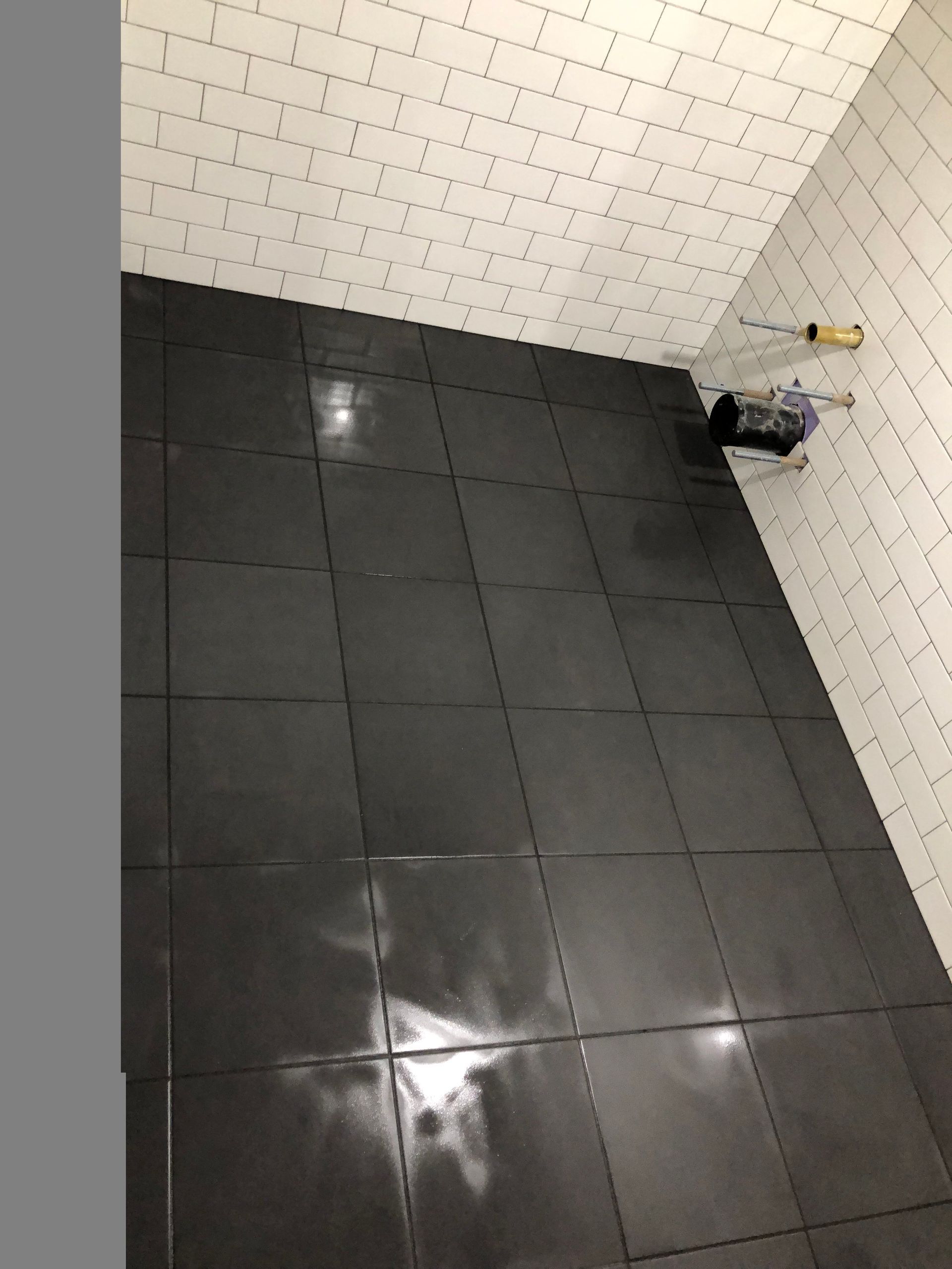 A bathroom with black tiles and white brick walls