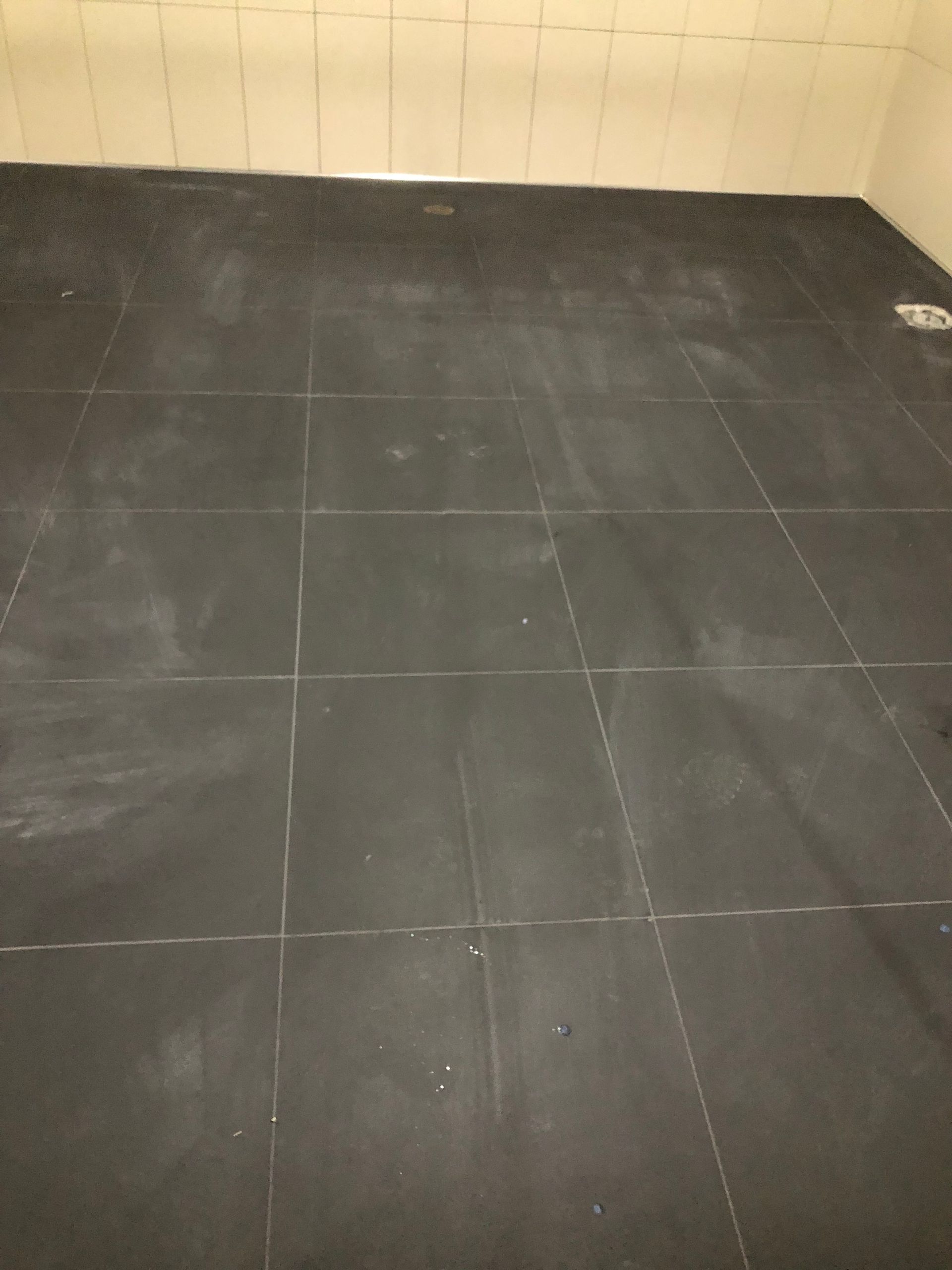 A black tiled floor in a bathroom with white tiles.
