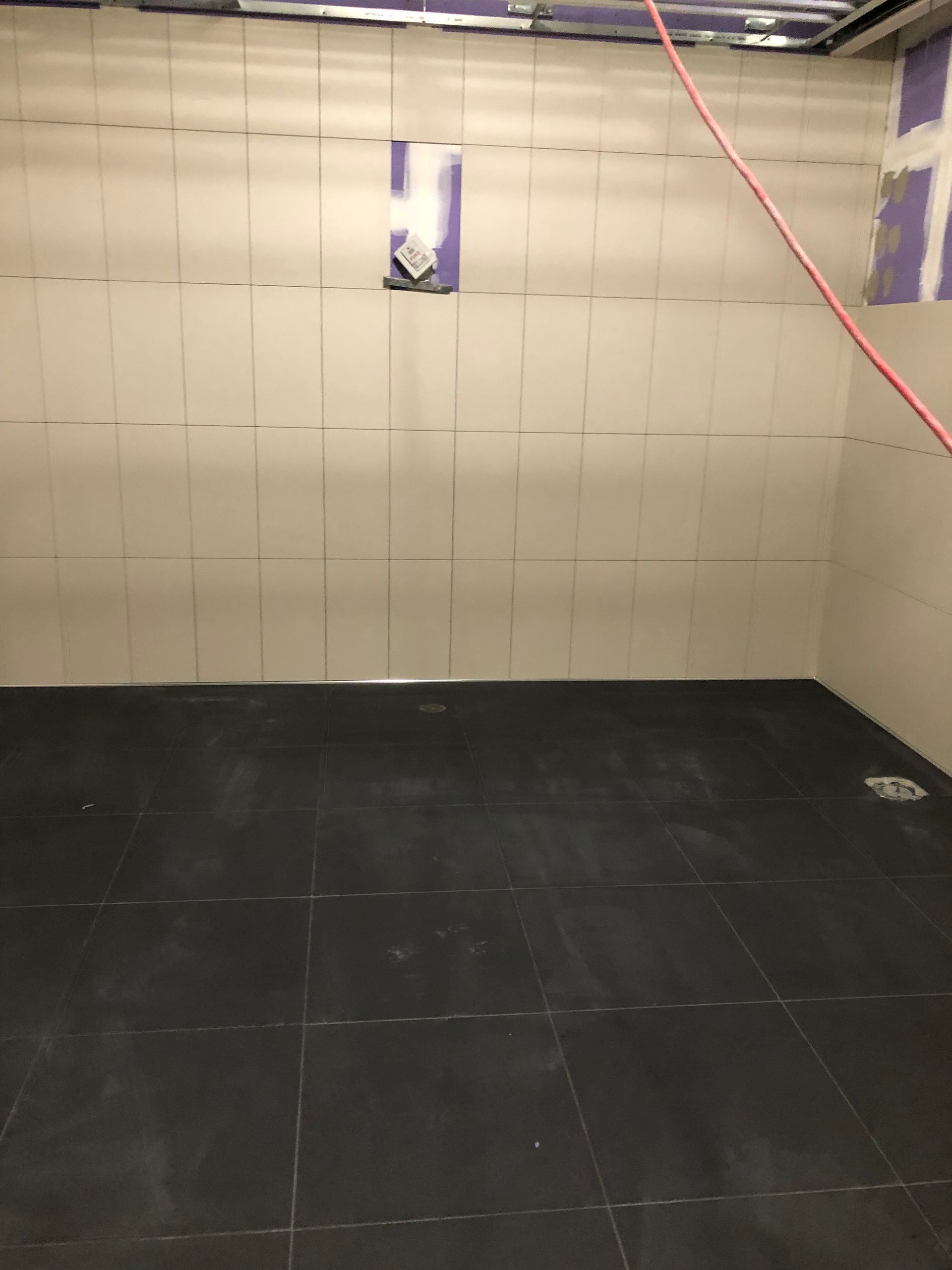 An empty room with a hose hanging from the ceiling.