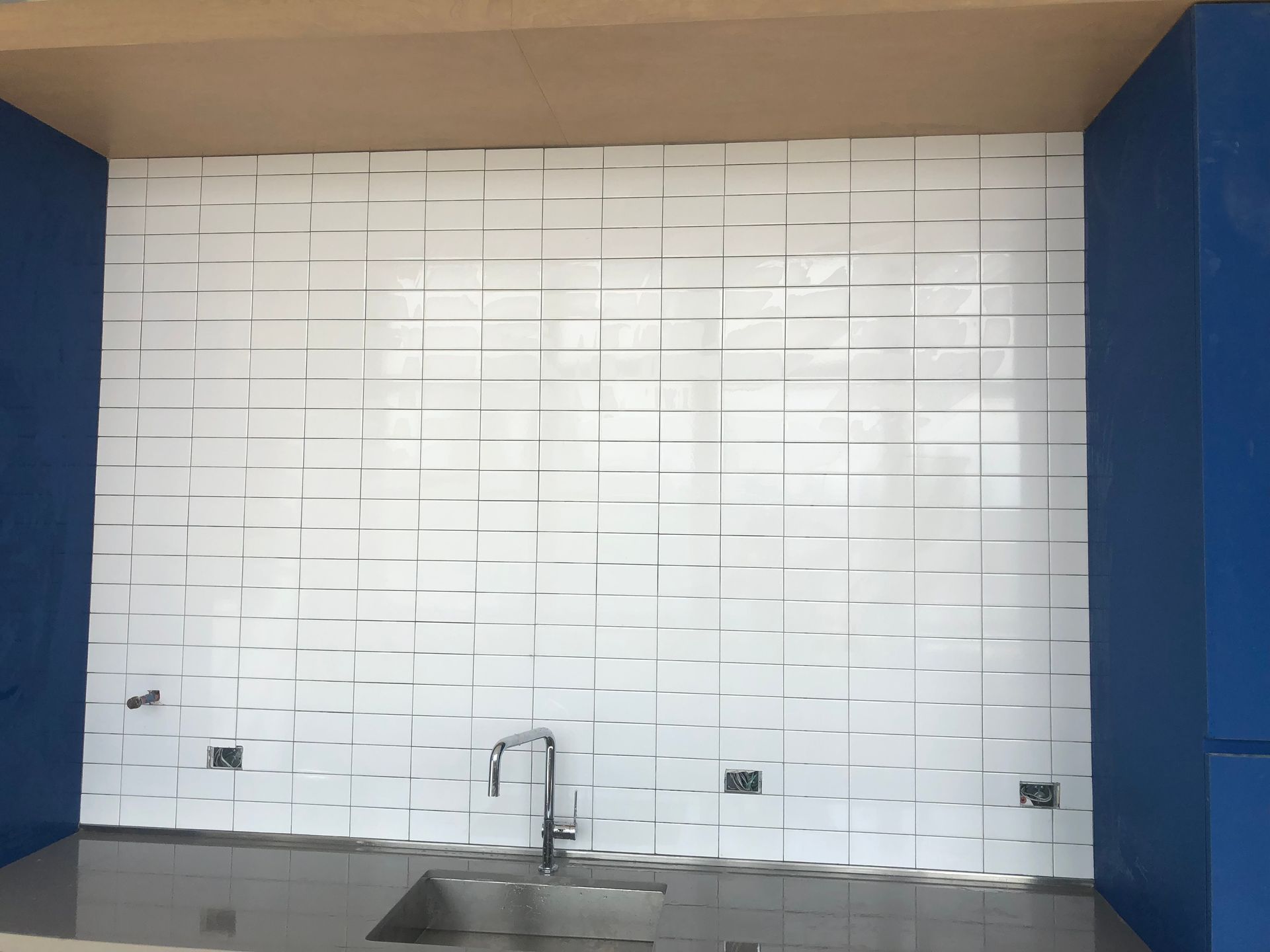 A kitchen with blue walls and white tiles on the wall