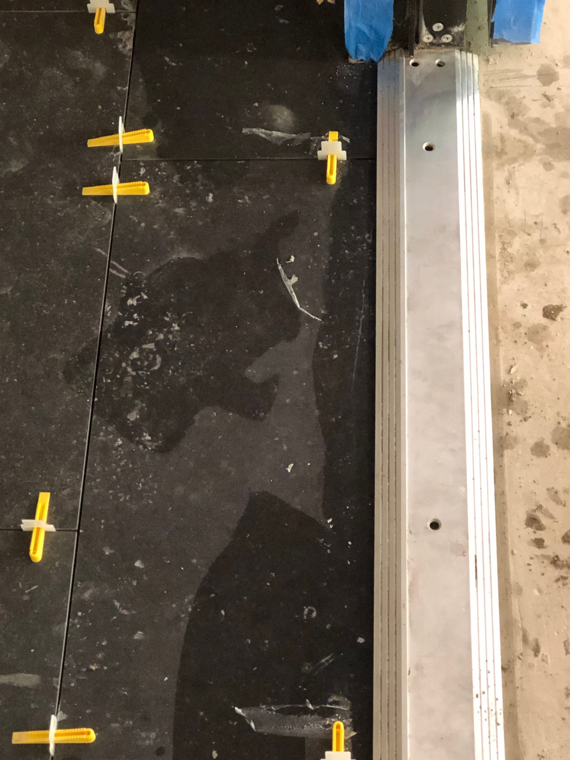 A black tile floor with yellow spacers on it
