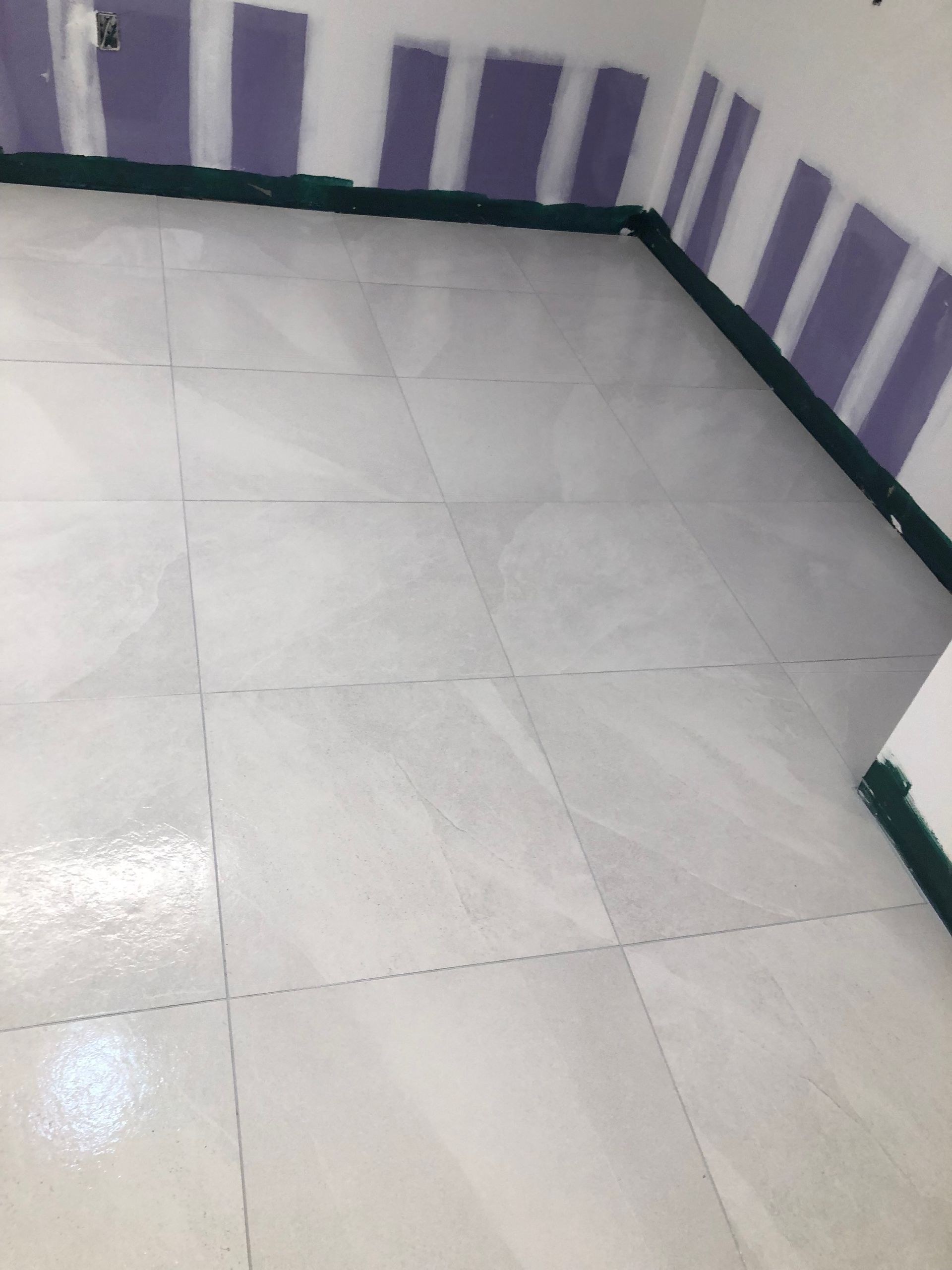 A white tile floor in a room with purple stripes on the walls.