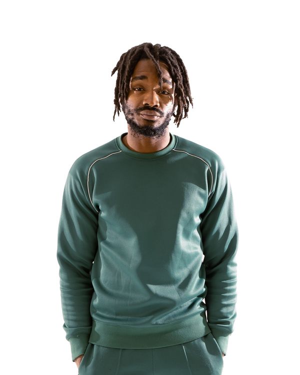 A man with dreadlocks is wearing a green sweatshirt