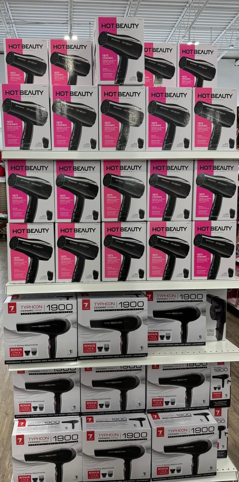 Hair dryers displayed on shelves in a store. Several boxes are stacked to show variety of the product.