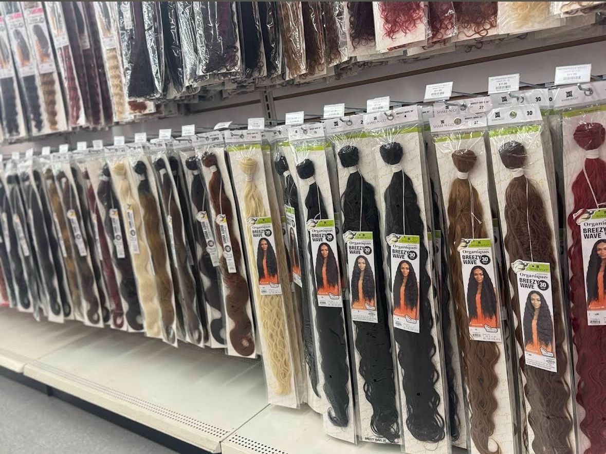 Shelves displaying various packaged synthetic hair extensions in a store.