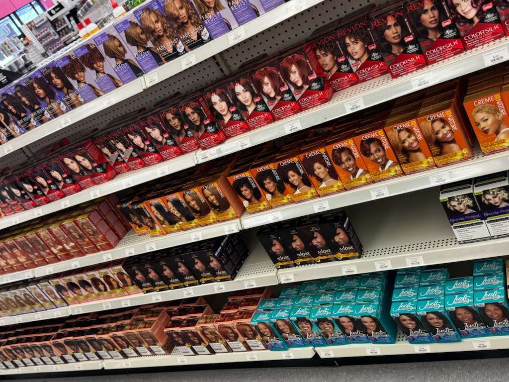 Shelves stocked with various boxes of hair dye in a store.