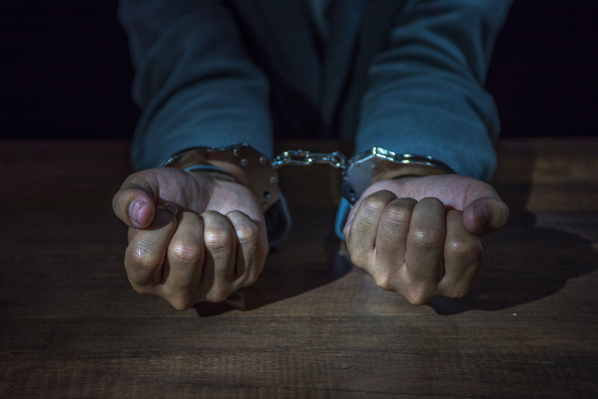 A man in handcuffs is sitting at a table – Saint Joseph, MO – Eslinger Law Firm