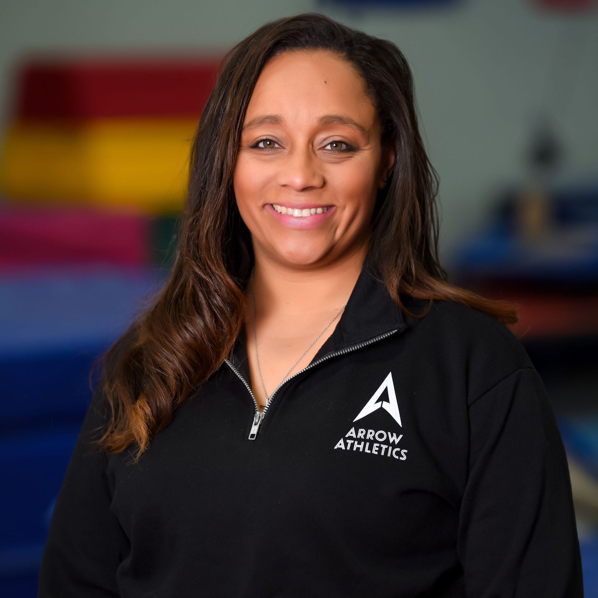 A woman wearing a black sweatshirt with the word arrow on it is smiling for the camera.