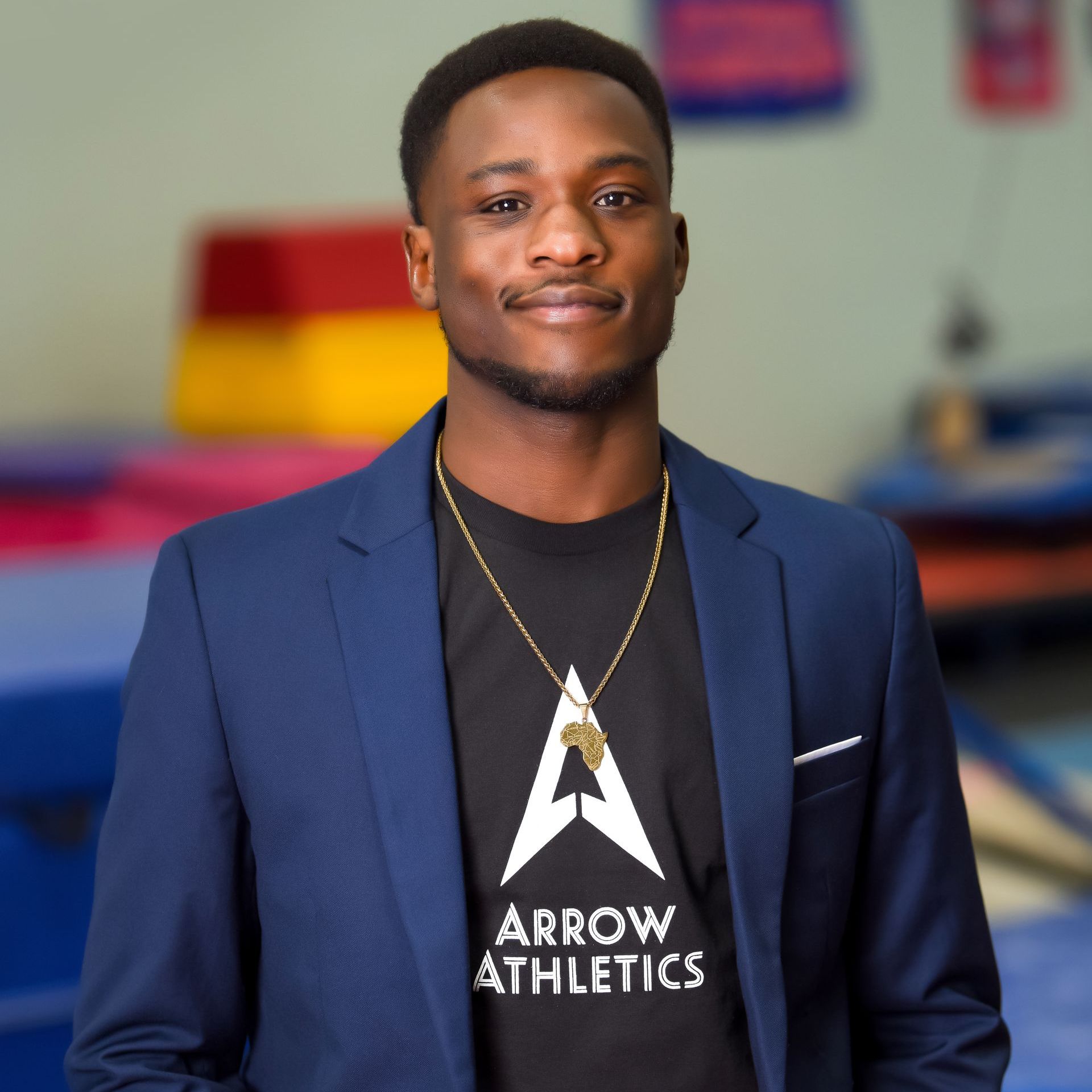 A man wearing an arrow athletics shirt and a blue jacket