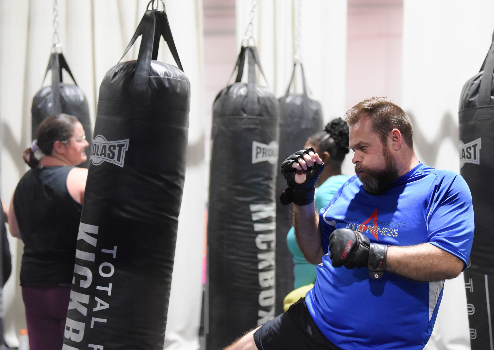 A man in a blue shirt is kickboxing in a gym.