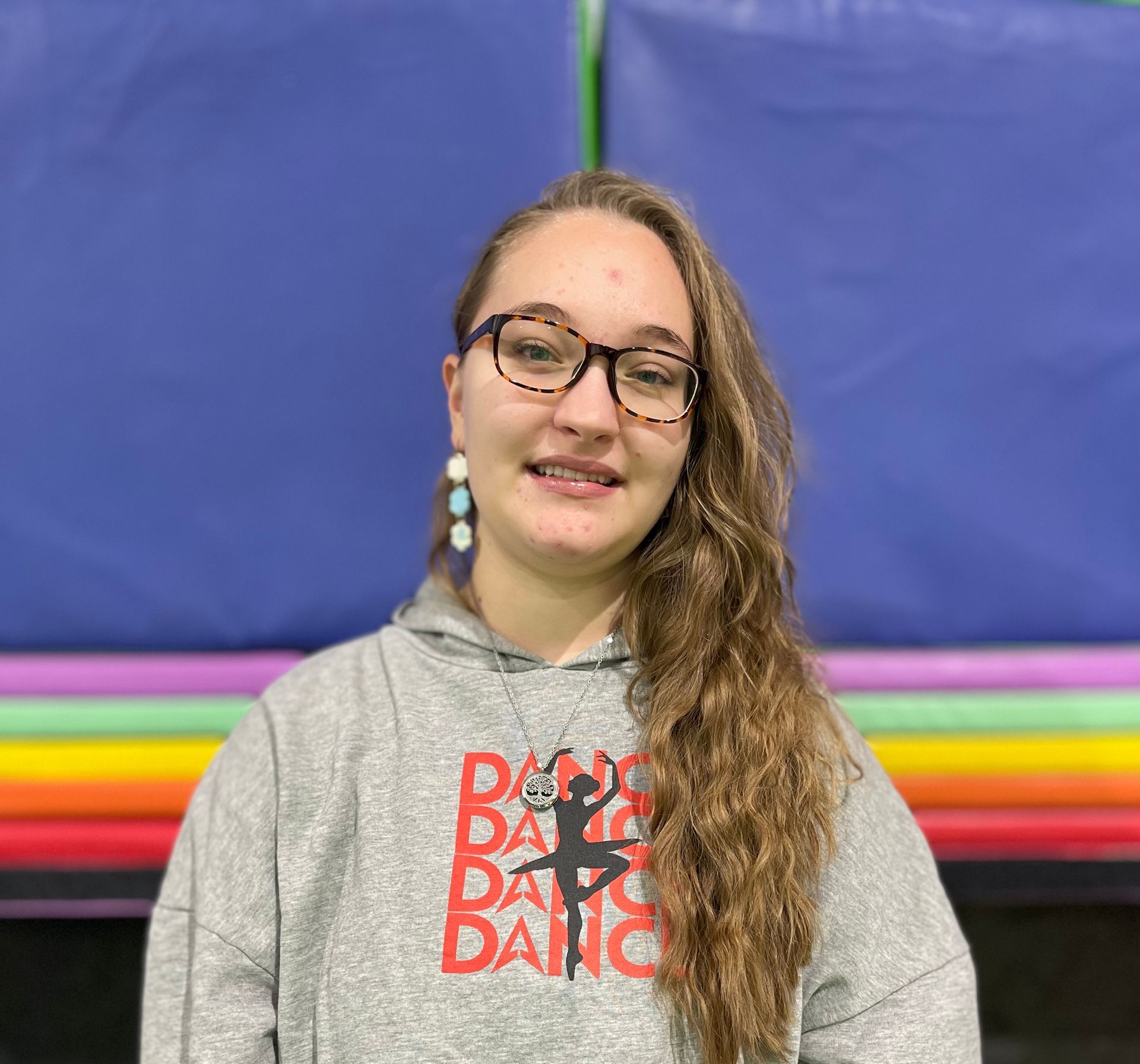 A young woman wearing glasses and a gray hoodie is posing for a picture.