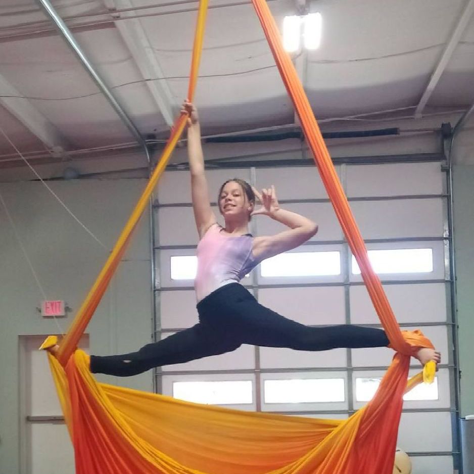 A woman is doing a split on an orange and yellow cloth