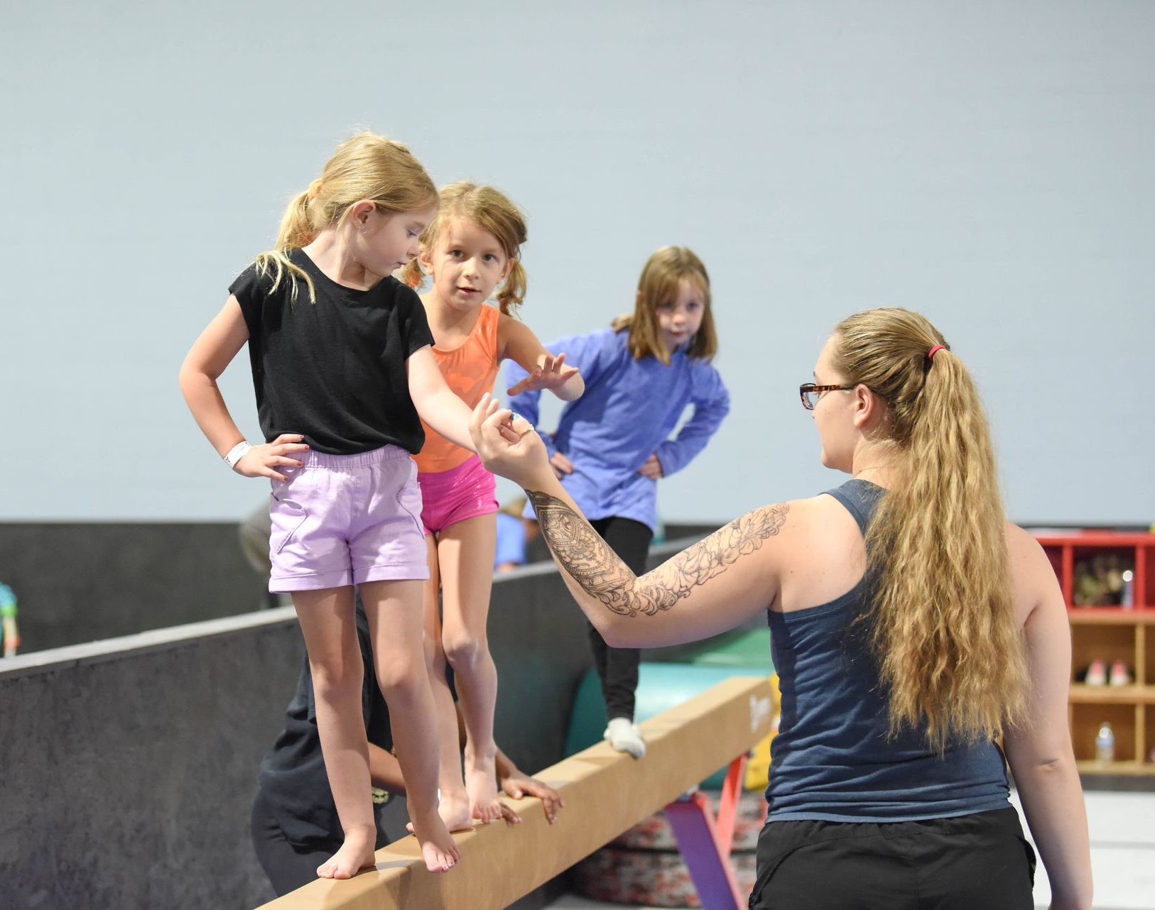 A group of young girls are standing on a balance beam.