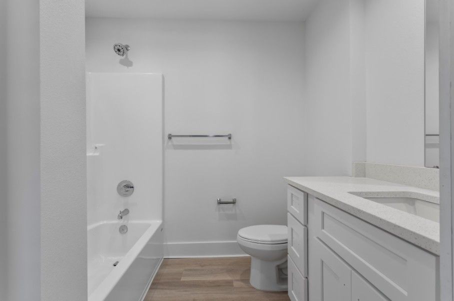 bathroom in apartment in Biloxi with quartz countertops, wood floors and a large soaking tub