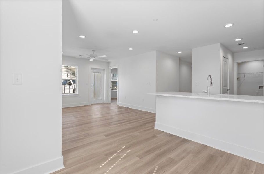 dine in kitchen peninsula in Biloxi with quartz countertops, white cabinets, wood floors and natural light coming in from patio door into living room