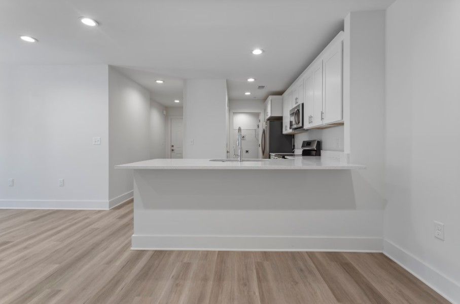 dine in kitchen peninsula in Biloxi with quartz countertops, white cabinets, wood floors and stainless steel appliances