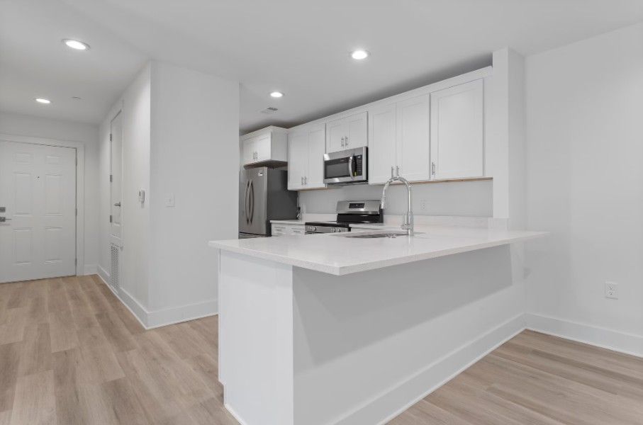 dine in kitchen peninsula in Biloxi with quartz countertops, white cabinets, wood floors and stainless steel appliances