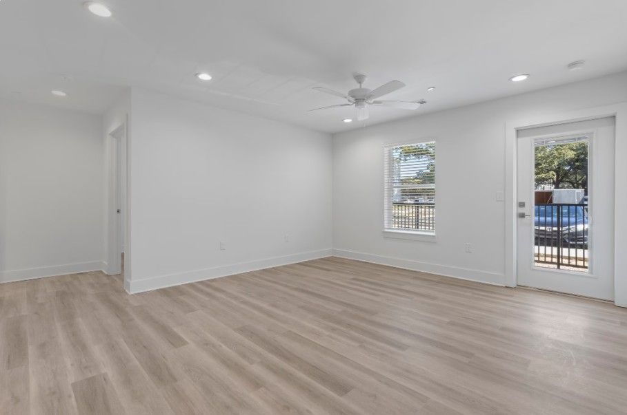 Large living room in Biloxi apartment with wood floors, painted white walls, and outside lounge area and ceiling fan