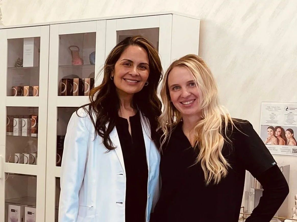 Two women smiling in a clinic setting.