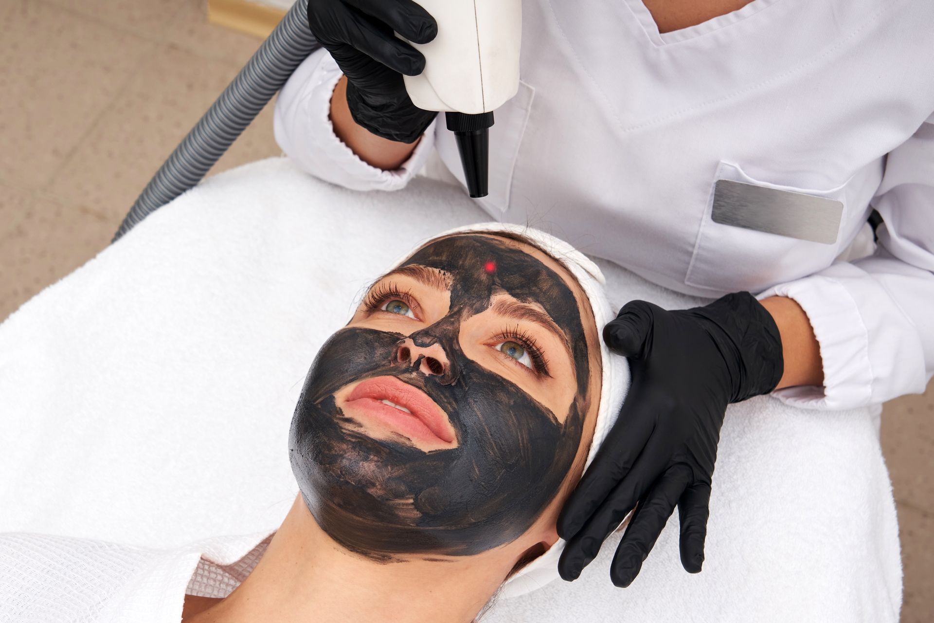 A woman is getting a black mask on her face.