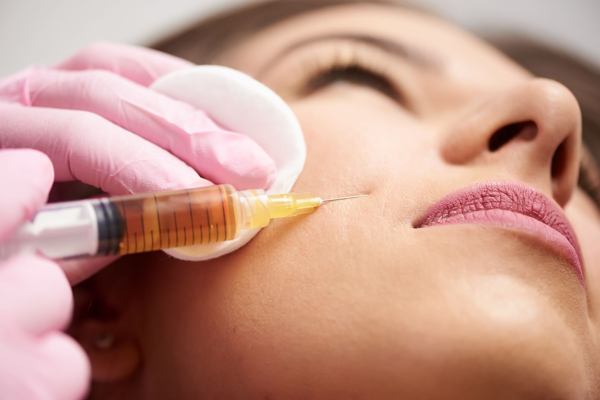 A woman is getting a botox injection in her face.