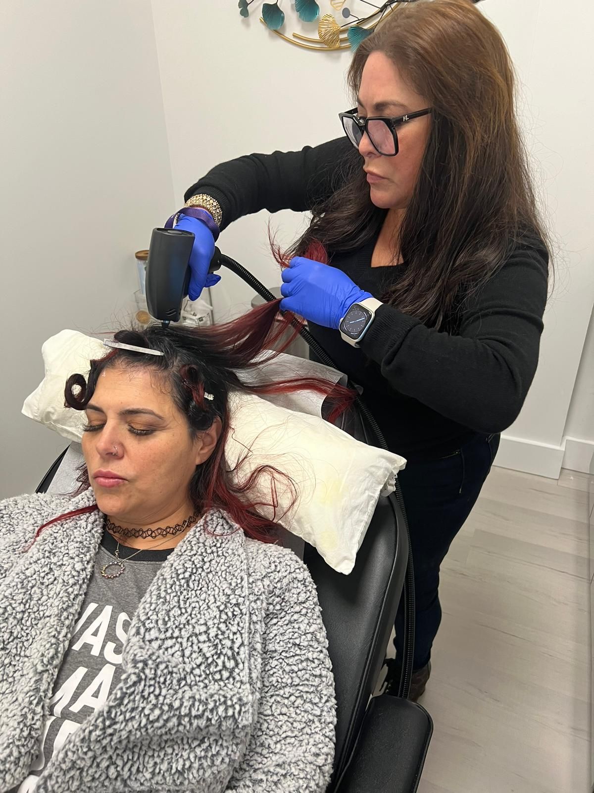 A woman is getting her hair done by a woman in a chair.