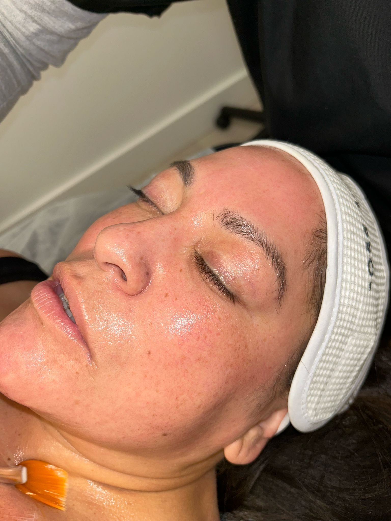 A woman is getting a facial treatment with her eyes closed.
