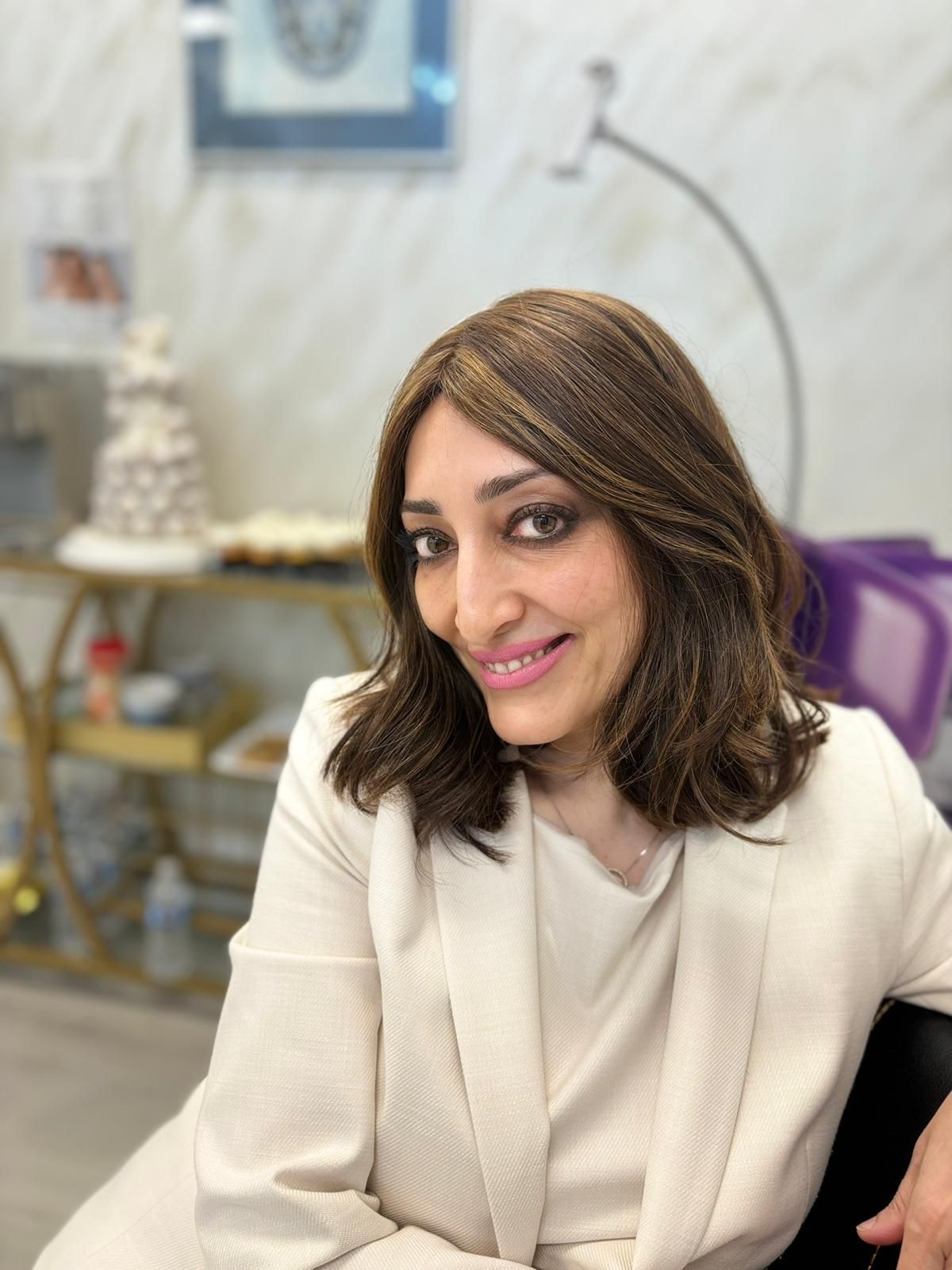 A woman wearing a wig and a white jacket is smiling for the camera.