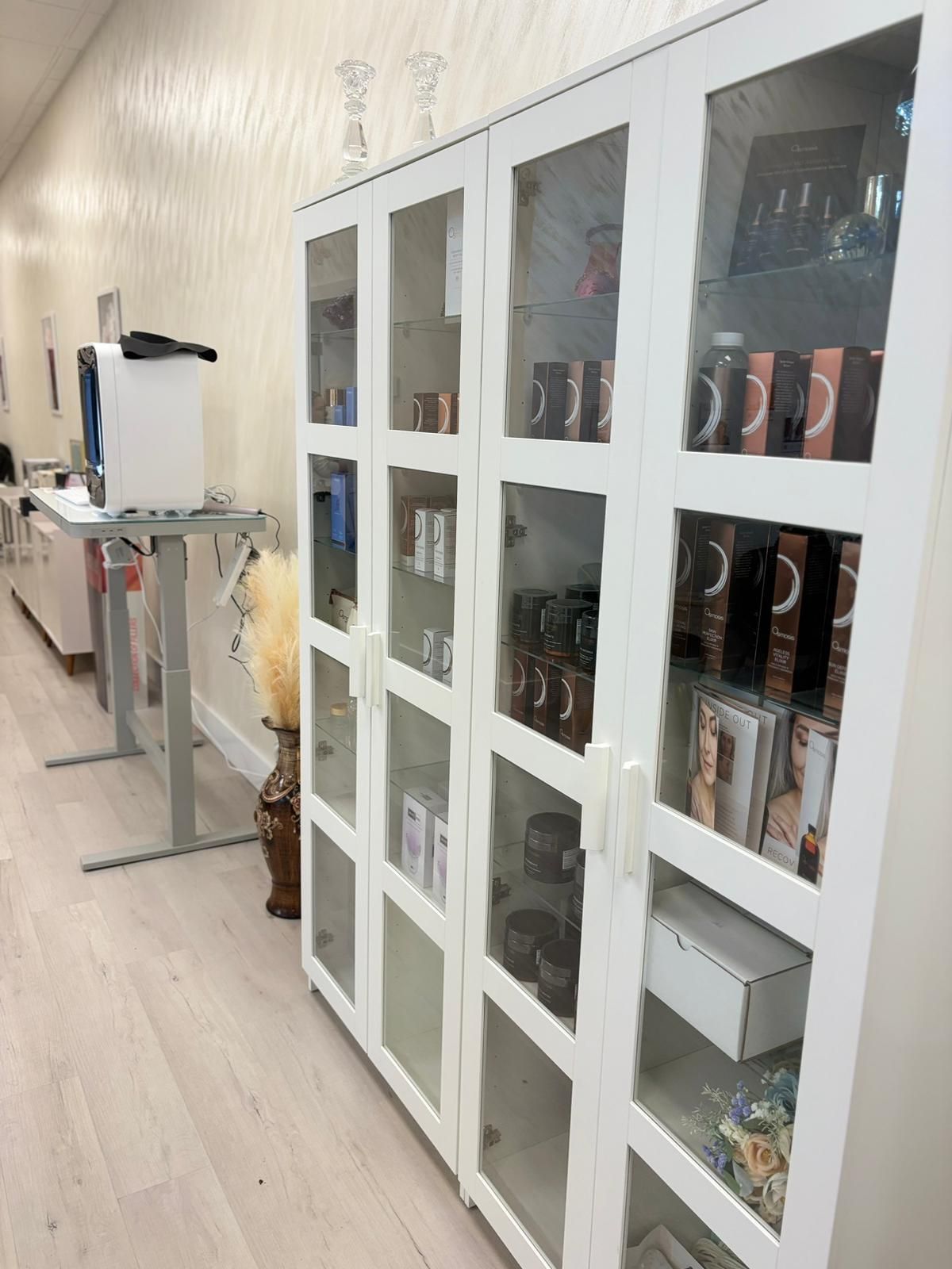 A row of white cabinets with glass doors filled with books.