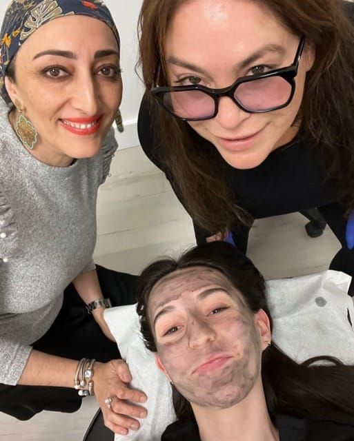 Three women posing for a picture with one wearing glasses
