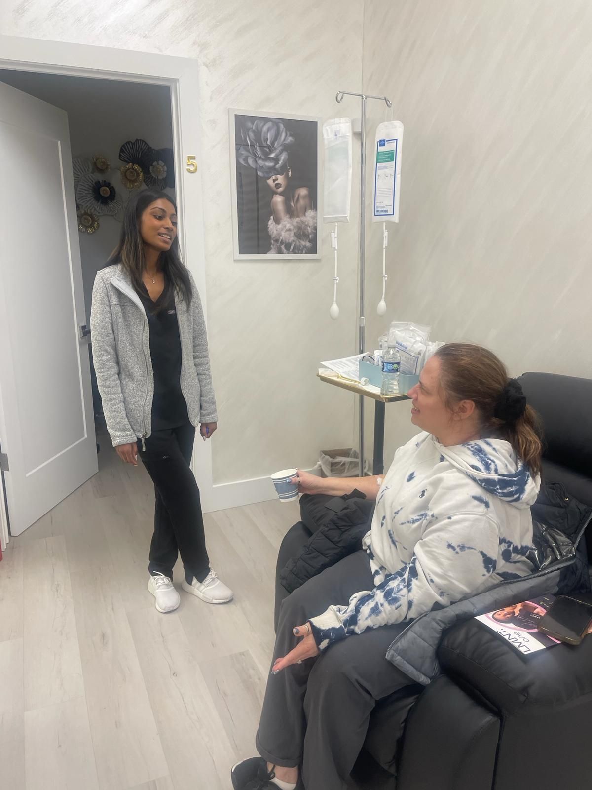 A woman is standing next to a woman sitting in a chair.