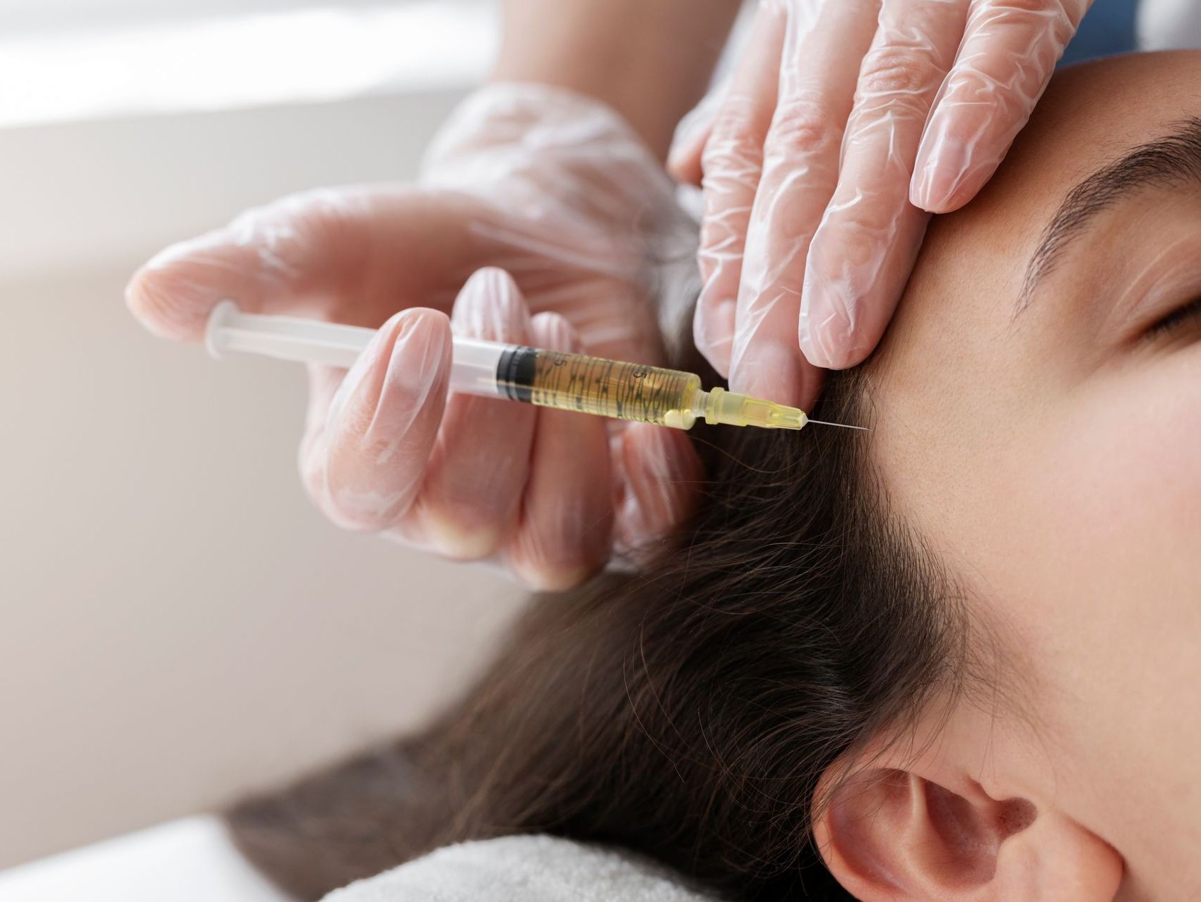 A woman is getting a botox injection in her forehead.