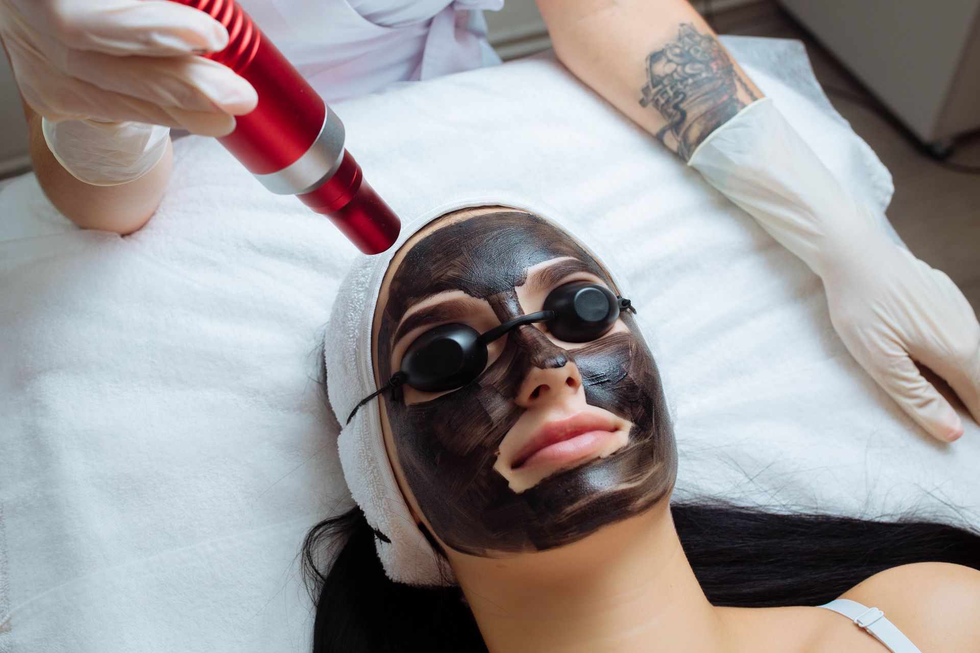 A woman is getting a black mask on her face.