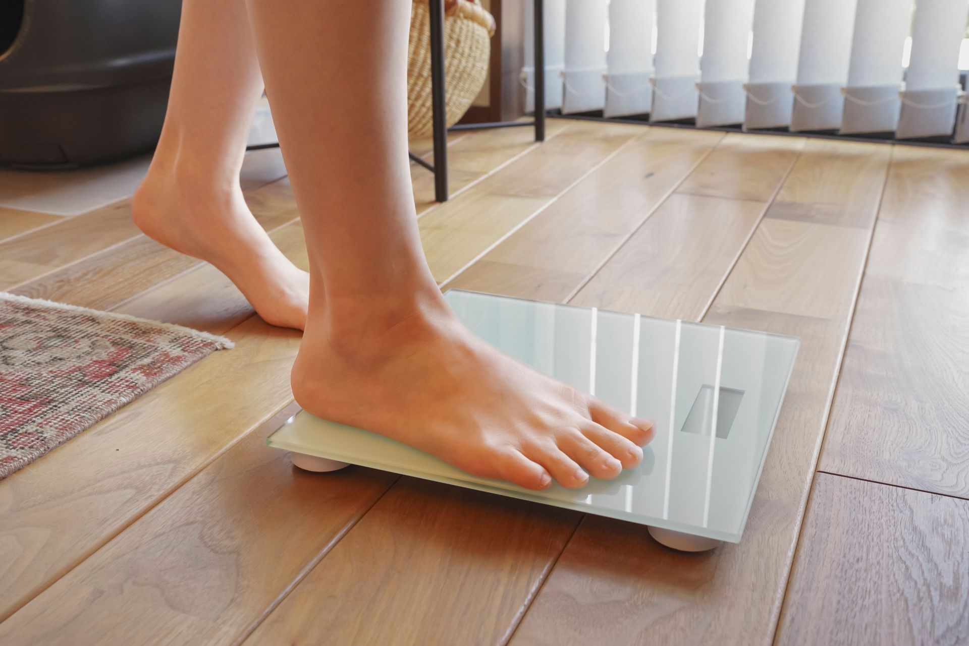 Bare foot stepping onto a digital bathroom scale on a wooden floor.