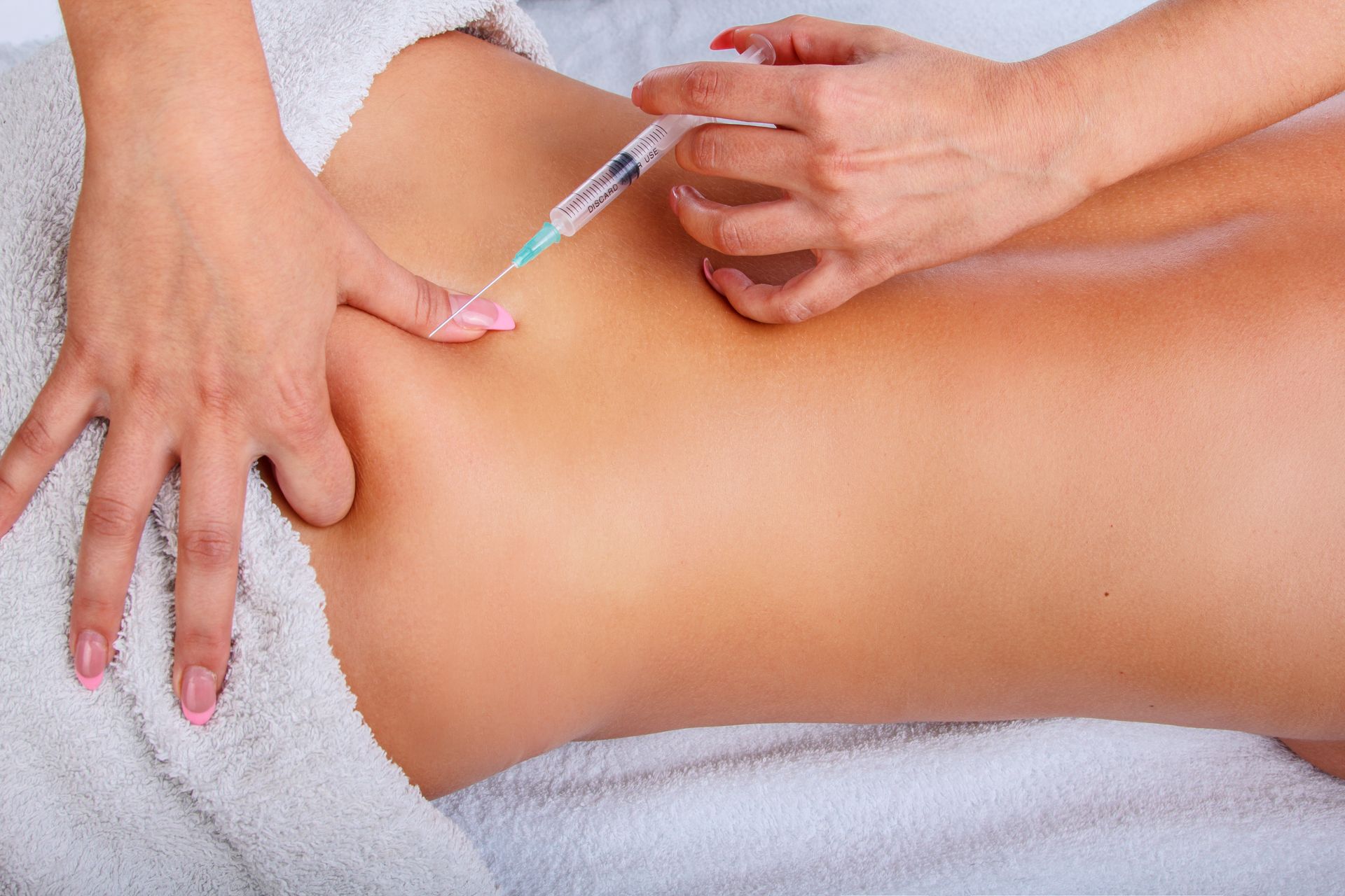 A woman is getting an injection in her stomach.