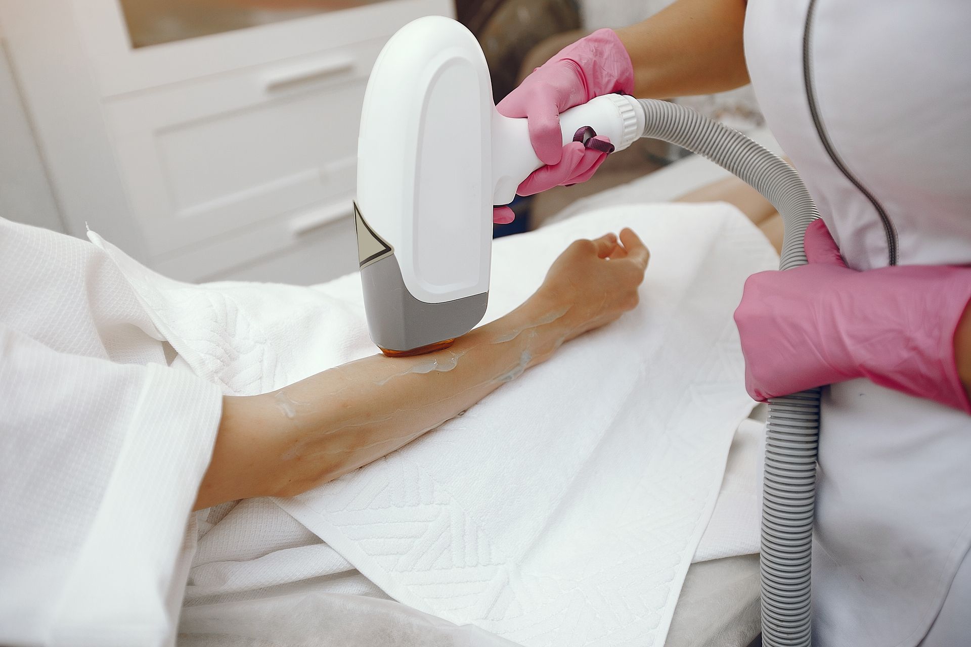 A woman is getting a laser hair removal treatment on her arm.