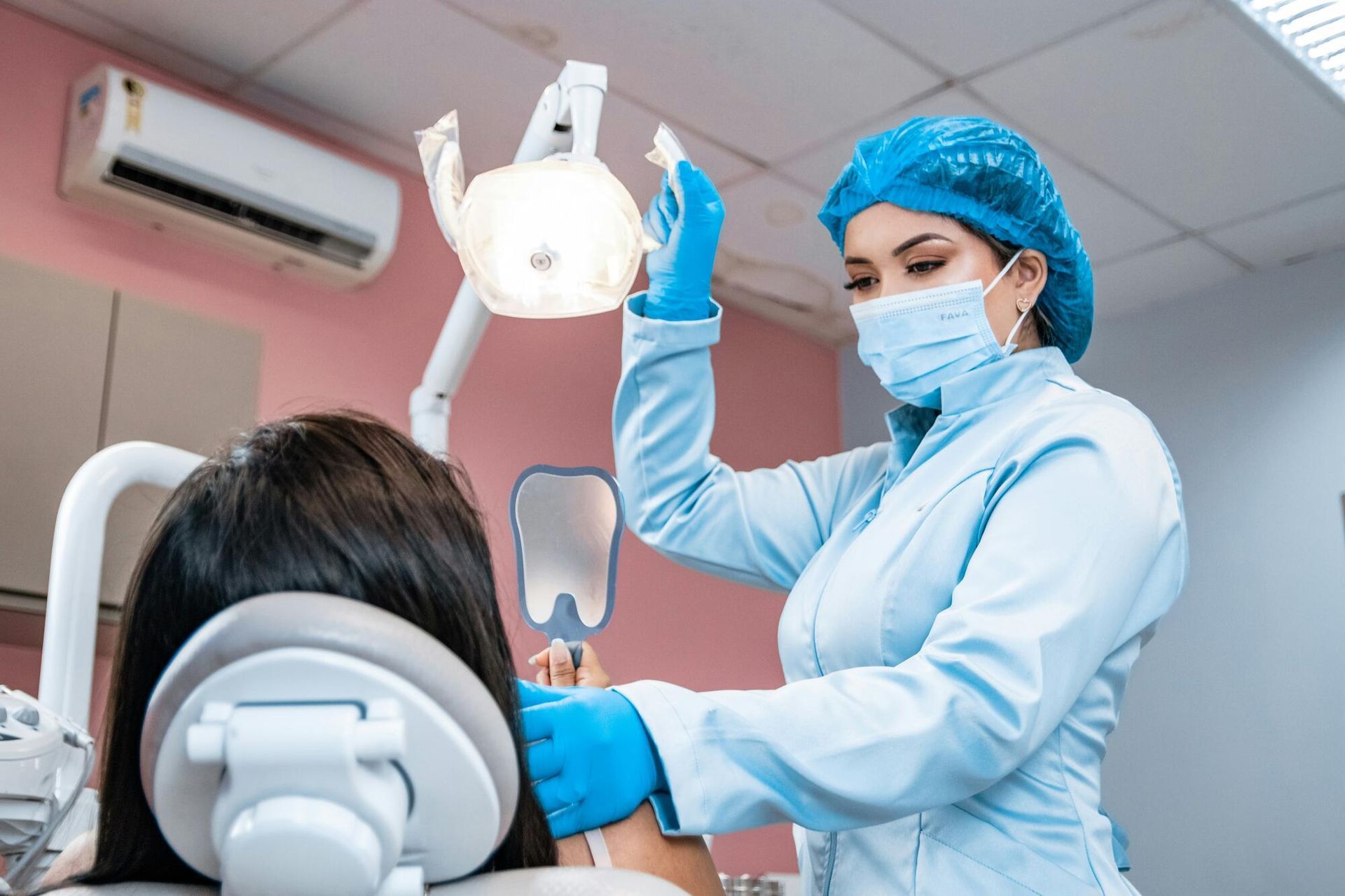 A dentist is examining a patient 's teeth in a dental office.