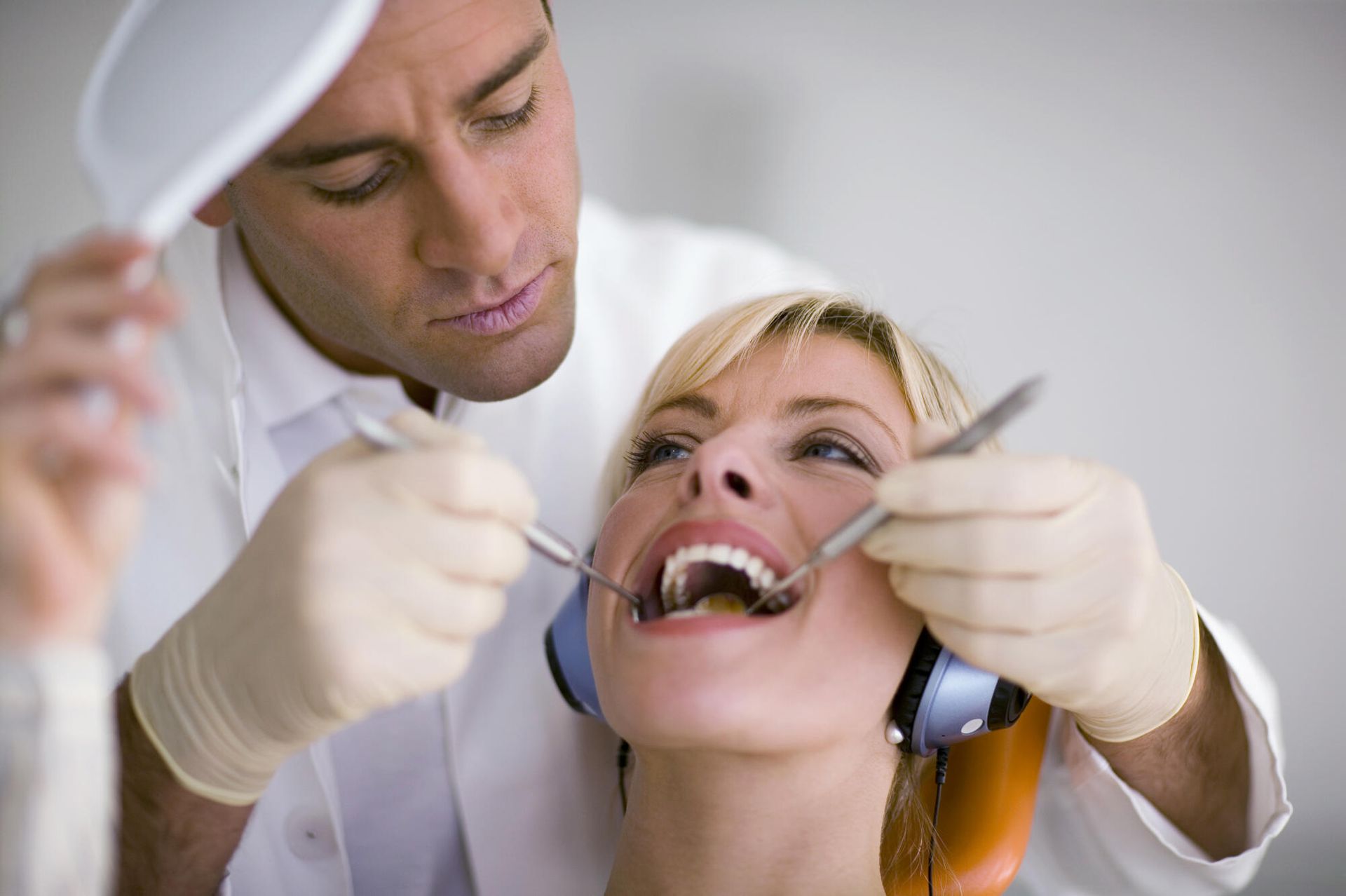 A woman is getting her teeth examined by a dentist.