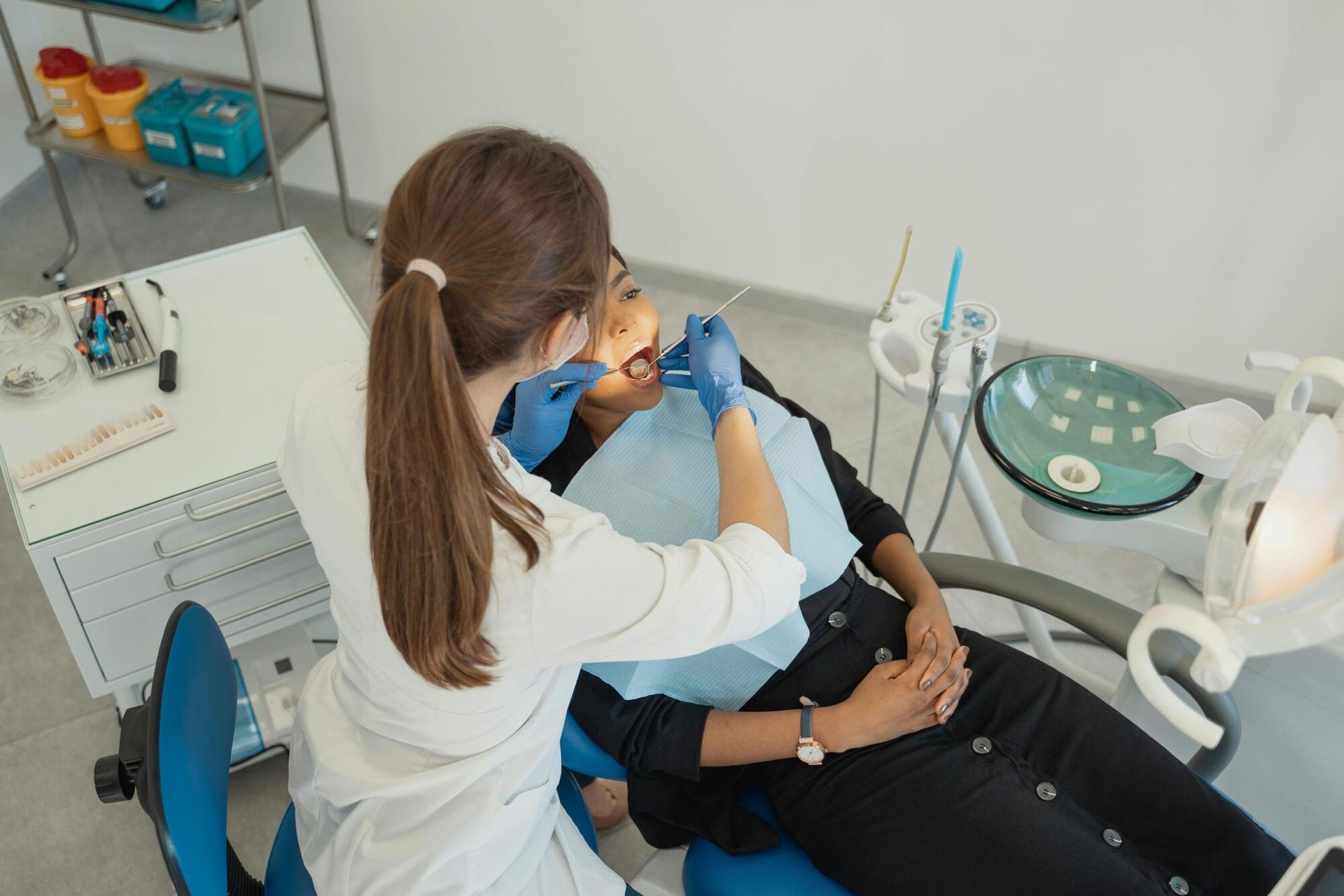 A woman is getting her teeth examined by a female dentist in a dental office.