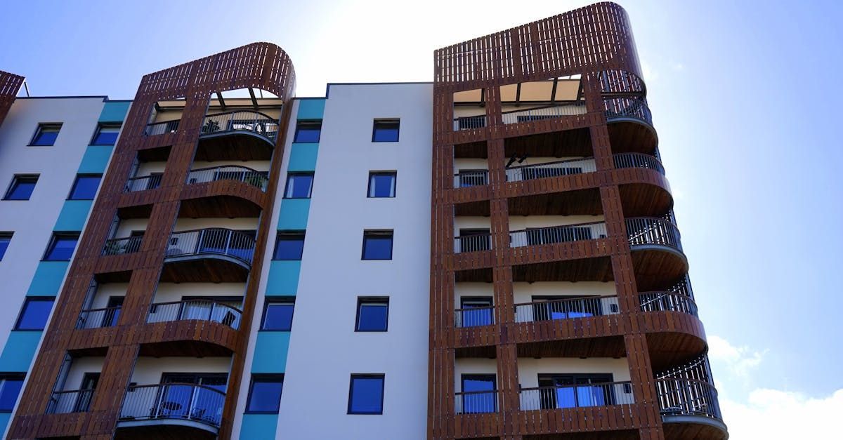 A tall building with balconies and a blue sky in the background