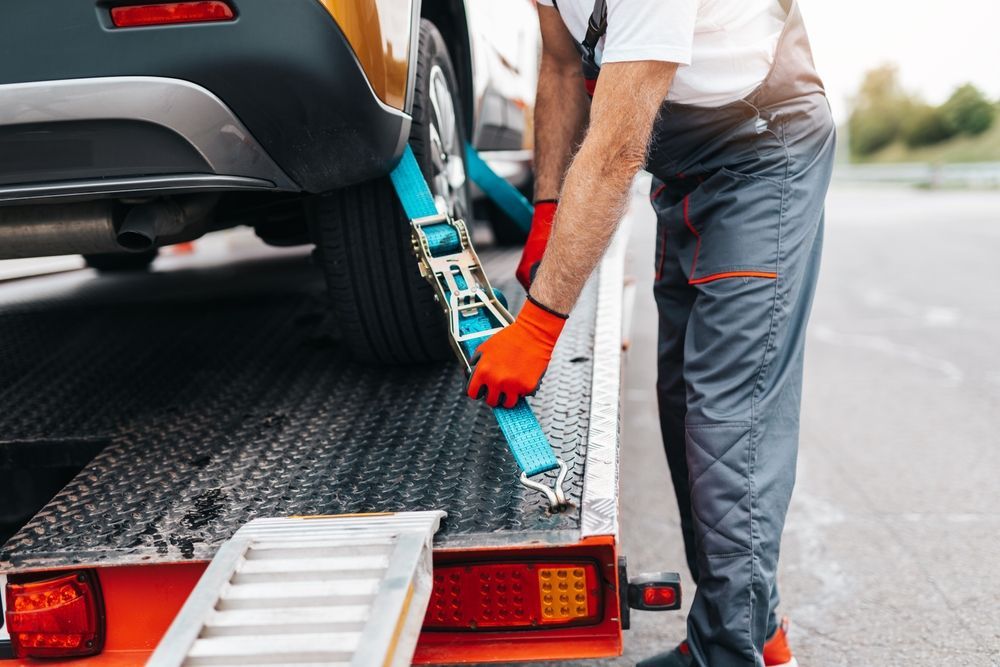 A man is tying a car to a tow truck.
