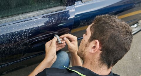 Two locksmith-repairmen workers installing house door lock using screwdriver