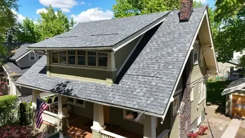 House with gray roof, green siding, and American flag on the porch.