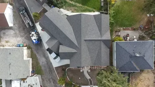Overhead view of a house with a newly installed dark gray roof. A truck is parked in the driveway.