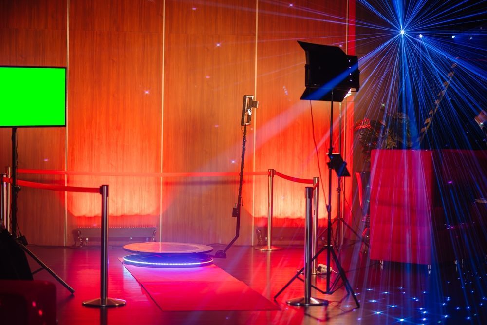 There is a red carpet in the middle of the room and a green screen tv.