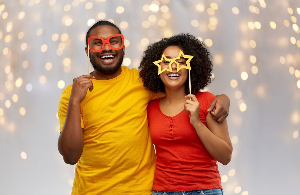 A man and a woman are posing for a picture while wearing fake glasses.
