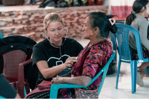 A woman is using a stethoscope to listen to an older woman 's heartbeat.